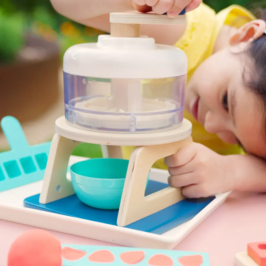 kid turning hand crank of pretend ice shave machine