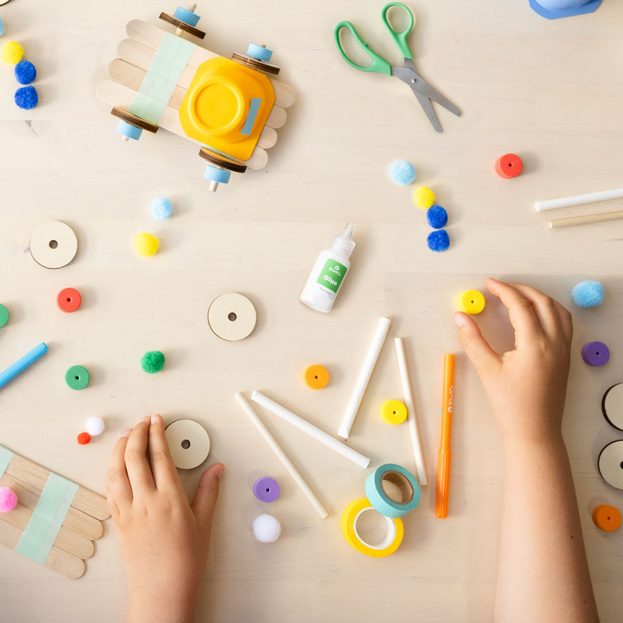 flatlay shot of pom-poms, scissors, glue, included in kit